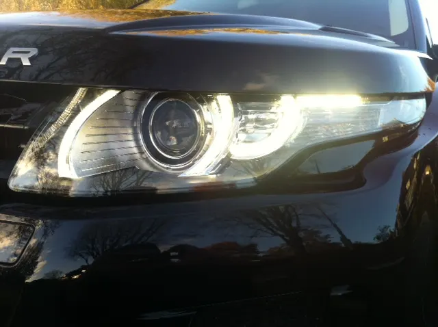 De brandende koplamp van een donkerblauwe Range Rover Evoque